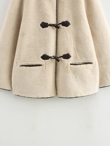Detail of faux fur coat featuring dark toggle buttons and contrasting leather trim