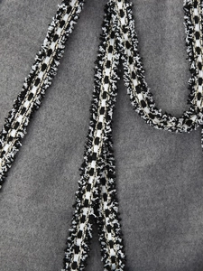 Detail shot of black and white woven trim with gold threads and fringe for woolen coats