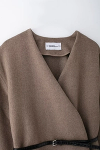 Close-up of brown wool coat with black faux-crocodile belt and metallic buckle detail
