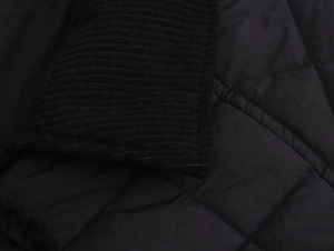 Macro detail of black quilted jacket showing contrast corduroy collar and rhombus stitching