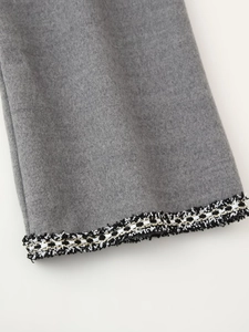 Macro detail of wool coat sleeve with decorative black white and gold woven braid trim