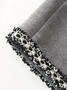Detail of grey wool coat featuring gold thread woven braid trim and fringe accents