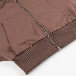 Dettaglio felpa con cappuccio marrone con texture in maglia e cerniera metallica
