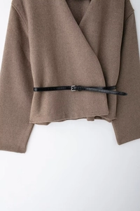 Detail of camel wool-like wrap top featuring a textured black leather belt with metal buckle