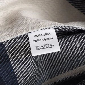 Detail van de 65% katoen 35% polyester textuur en het wasvoorschrift van de geruite jas