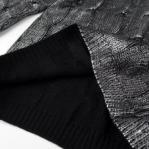 Detailed macro view of black knit sweater with silver metallic coating and cable textures