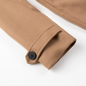 Detailed close-up of camel wool coat cuff featuring decorative tab and black button