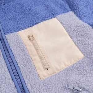 Close-up of contrast faux shearling jacket with blue grey panels and chest zip pocket