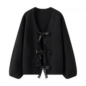 Detailed view of black knitted cardigan featuring sequined bow-tie closures and ribbed cuffs