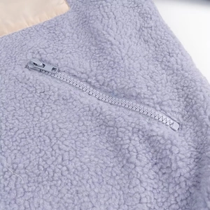 Detail of lilac sherpa fleece jacket featuring a contrast zipper pocket and soft texture