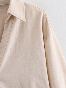 Close-up of linen fabric texture on a beige button-down shirt with lapel details