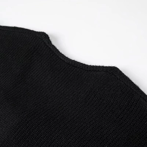 Close-up of the neck collar on a black knit cardigan with textured wool fabric detail