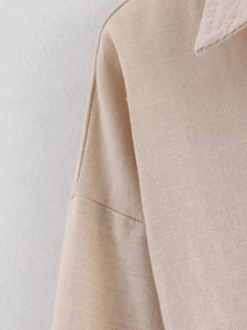 Detailed macro shot of beige linen shirt shoulder stitching and fabric texture