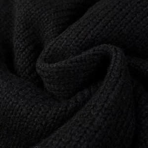 Macro shot of high-density black knitted fabric texture on the winter cardigan