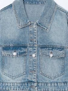 Close-up of light blue washed denim jacket with flap pockets and metallic buttons