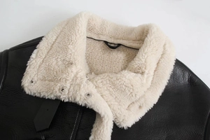 Detail of black pebbled leather jacket with plush cream faux fur collar and silver snap