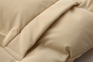 Close-up of beige quilted vest showing premium double stitching and matte fabric texture