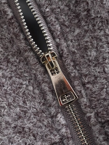 Close-up of durable metal zipper on a dark purple sherpa fleece jacket texture