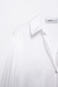 Gros plan du col d'une chemise en satin de soie blanc montrant la texture et l'étiquette