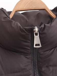 Detail of high collar and metal zipper on black padded vest with a glossy finish