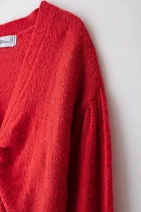 Dettaglio ravvicinato del cardigan rosso in maglia con trama morbida ed etichetta