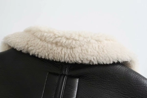Close-up of winter jacket featuring black faux leather and white shearling fleece collar