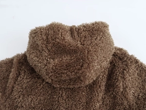 Detail shot of deep brown faux fur hooded coat showing soft curly fiber texture