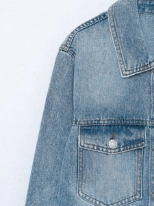 Detail of light blue denim jacket showing collar, chest pocket and stitching textures