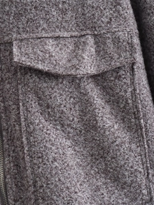 Detailed macro view of dark taupe fleece jacket fabric with pocket and metal zipper edge
