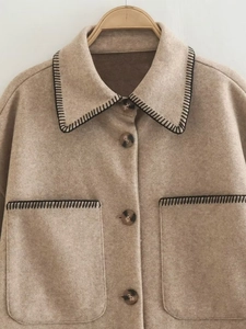 Detail of oat wool coat featuring black contrast stitching and marble texture buttons