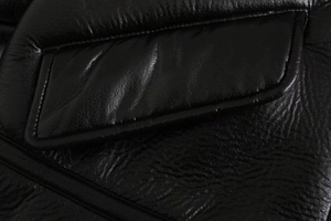 Detailed close-up showing natural grain and stitching on black faux leather jacket