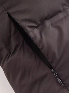 Detail of hidden zipper pocket on black quilted winter vest with seamless stitching