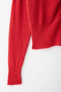 Dettaglio macro di maglione rosso lavorato a maglia con polsini a costine fini