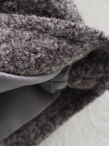 Detailed macro view of plush dark grey teddy wool fabric with smooth satin lining