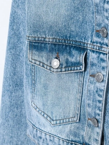 Detailed close-up of the front chest pocket and embossed silver buttons on denim jacket