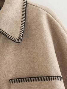 Detail view of camel wool jacket featuring premium texture and black blanket stitch edges