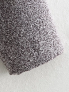 Macro shot of grey-purple bouclé fabric texture on a winter jacket cuff