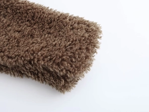 Detailed macro view of dark brown curly faux fur texture and thick warm fabric material