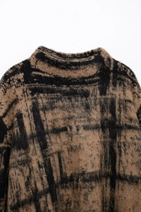 Detail shot of the brushed mohair texture and abstract black pattern on the knit sweater