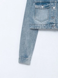 Detail of light blue denim jacket showing metal buttons and premium contrast stitching
