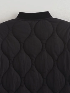 Detail of black quilted jacket featuring onion-pattern stitching and a ribbed knit collar