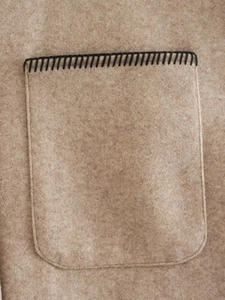 Close-up of wool blend coat detail featuring contrast black stitching on pocket edge