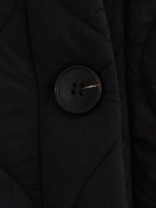 Detail of diamond quilted fabric with a high-quality dark tortoiseshell button on a coat