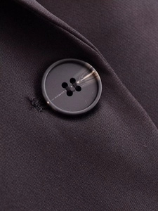 Detailed macro view of a marble-textured resin button on a dark tailored blazer fabric