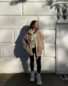 Close-up of a stylish women's beige fleece jacket with stand collar and double zipper