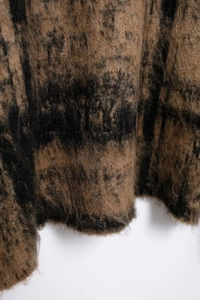 Close-up of soft plaid knit fabric with fuzzy mohair texture in brown and black