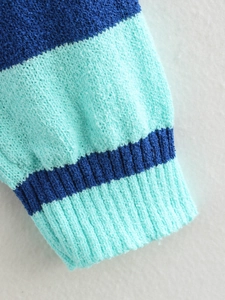 Detailed macro view of the blue striped knit cardigan featuring ribbed cuffs and soft texture