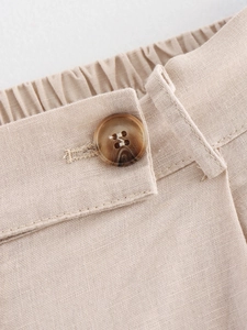 Detail of linen pants showing elastic waistband and marble button with engraved text