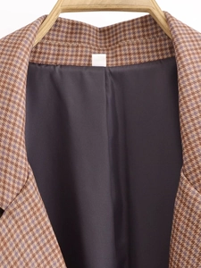 Detail of houndstooth blazer collar with high-quality stitching and dark smooth lining