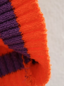 Detailed macro view of vibrant orange and purple bouclé knit fabric with plush texture